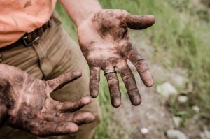 overhead view of a mans hands caked in dirt