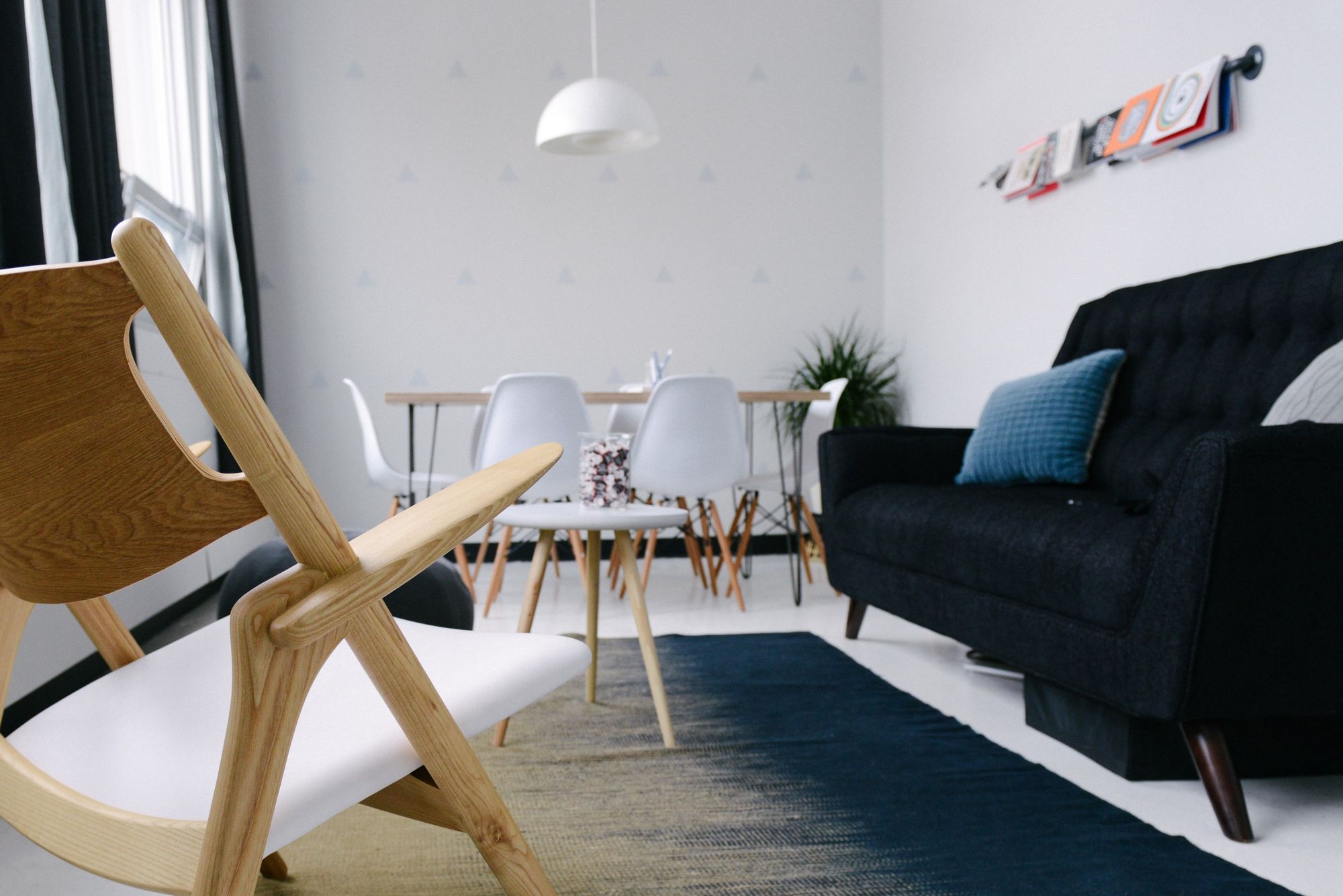 A clean bright office with lots of post modern chairs and a coach. Off to the right side there are some graphic swatch books hanging from a rod on the wall